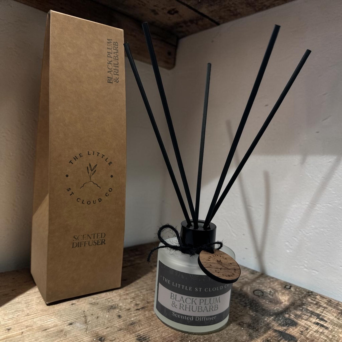 Scented diffuser with black reeds and packaging on a wooden surface