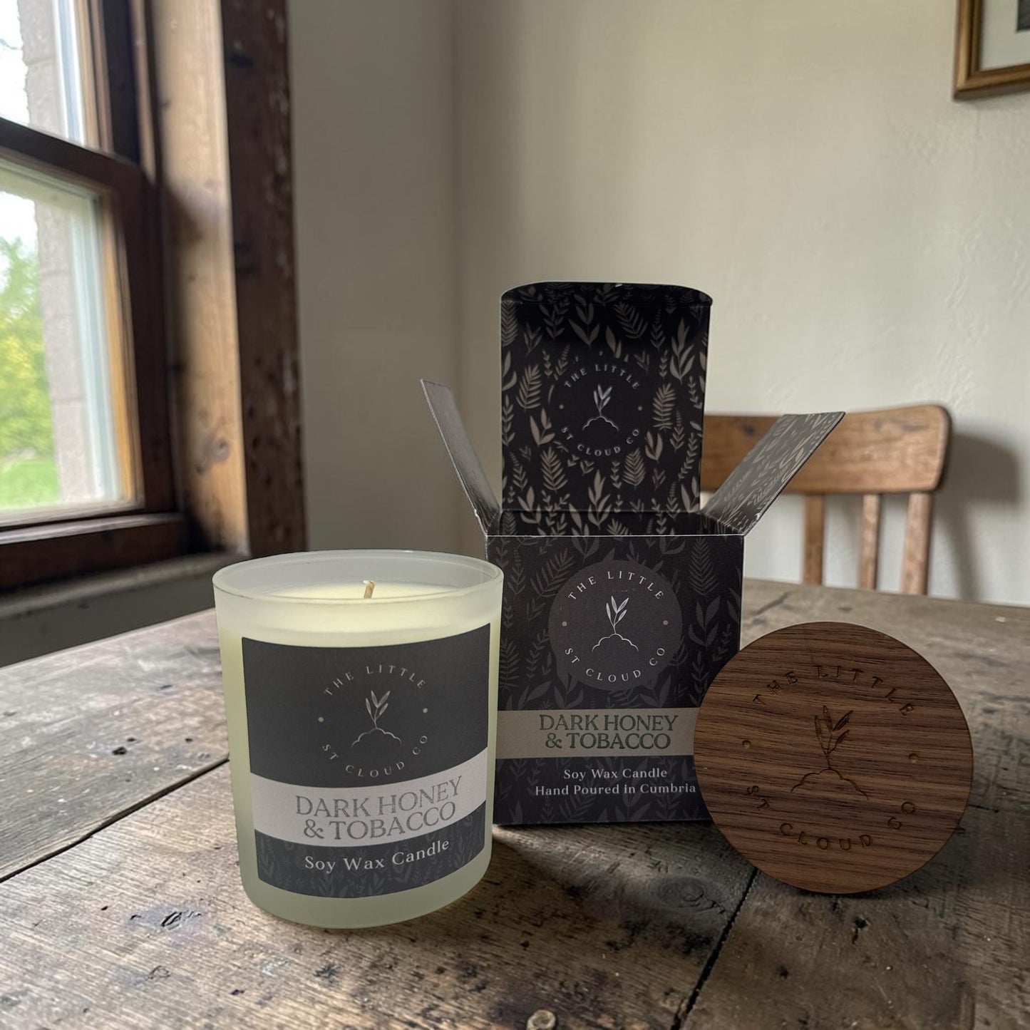 Dark honey and tobacco candle with packaging on a wooden table