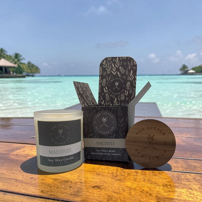 Candle and packaging with 'The Little St Cloud Co' branding against a beach backdrop