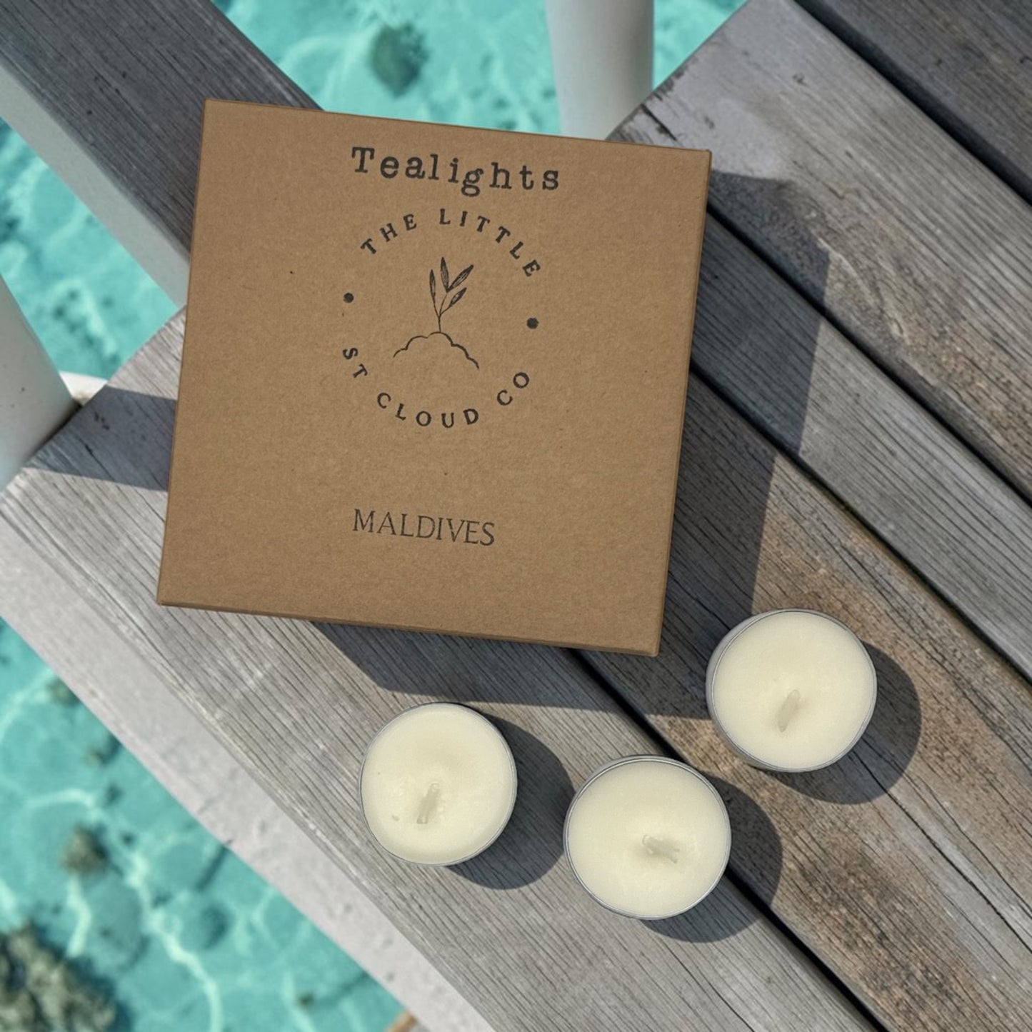 Tealights from The Little Cloud Co. on a wooden surface with the sea in the background