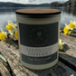 A frosted candle jar with wooden lid scented Ullswater Daffodils by the little st cloud co with a lakeside view with daffodils
