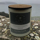 A frosted candle jar by the little st cloud co in the scent windermere mist sat on a stone wall with misty lake views