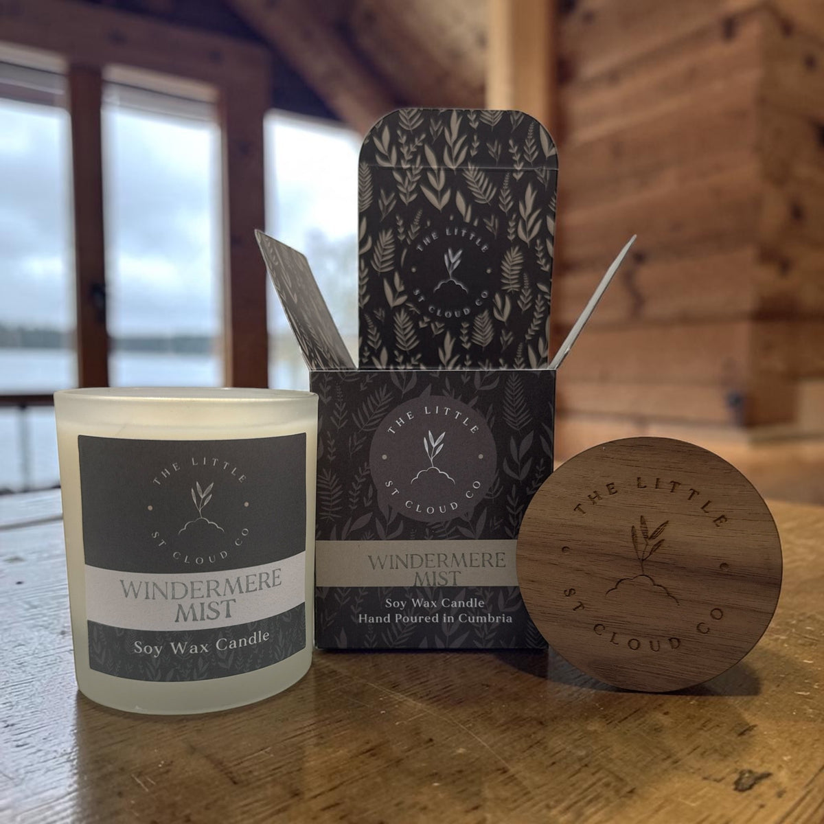 A frosted candle jar with gift box and wooden lid by the little st cloud co in the scent windermere mist in a lakeside lodge with lake side views