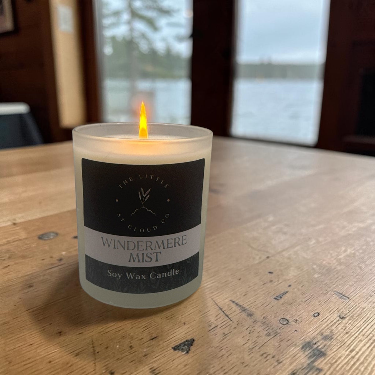 a lit frosted candle jar by the little st cloud co in the scent windermere mist with lake views
